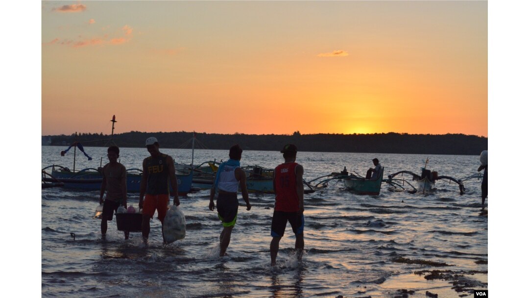 At sunset on the shores of Masinloc town fishermen return from a day of fishing nearby in the South China Sea, while others head out for overnight fishing, Masinloc, Philippines, Nov. 8, 2015. (S. Orendain/VOA)