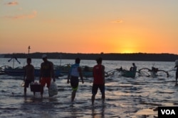 At sunset on the shores of Masinloc town fishermen return from a day of fishing nearby in the South China Sea, while others head out for overnight fishing, Masinloc, Philippines, Nov. 8, 2015. (S. Orendain/VOA)