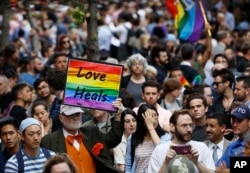 A man walks through the crowd holding a sign during a vigil and memorial for victims of the Orlando nightclub shootings near the historic Stonewall Inn in New York, June 13, 2016.