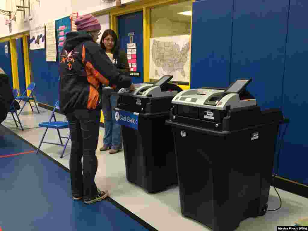 Une femme vote sur un ordinateur au bureau de vote de Barcroft, à Arlington, Virginie, le 8 novembre 2016 (VOA/Nicolas Pinault)