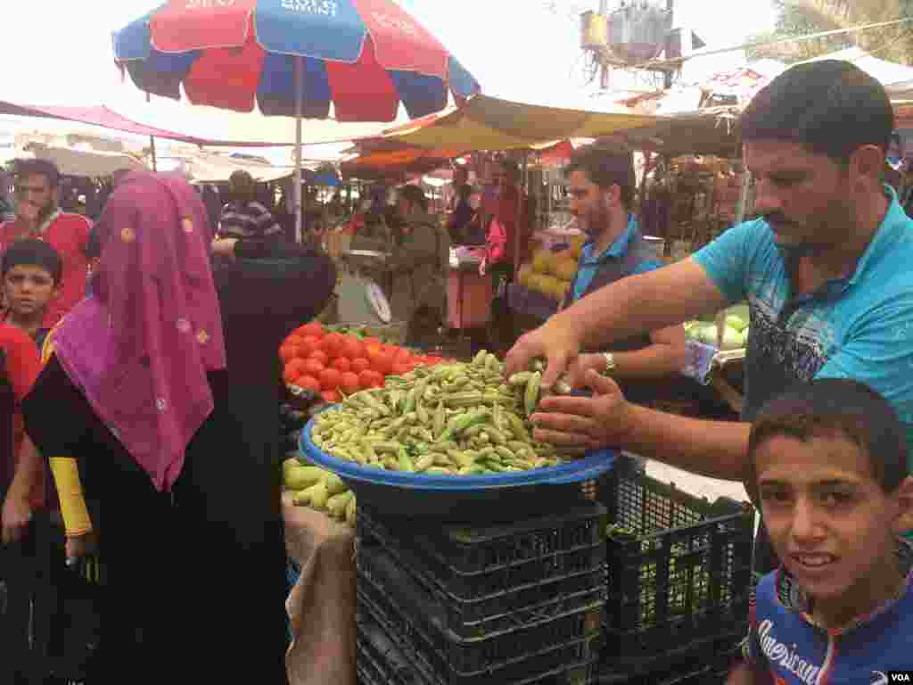 Seorang pria membeli okra di pasar sayur di wilayah Al-Zahra (bagian kiri Mosul), 19 Juli 2017.