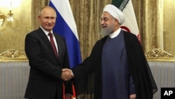 FILE - In this Nov. 1, 2017 file photo released by an official website of the office of the Iranian Presidency, Iran's President Hassan Rouhani, right, shakes hands with Russian President Vladimir Putin, at the Saadabad Palace in Tehran.
