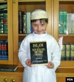 Seorang anak laki-laki muslim menunjukkan buku: 'Islam in New Zealand, the First Mosque' di Masjid Canterbury, Selandia Baru.