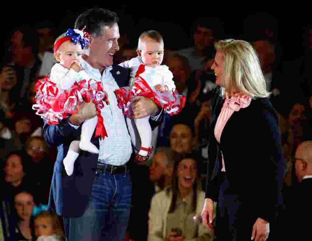 Mitt Romney dan istrinya Ann menggendong bayi-bayi yang dipilih dari kerumunan pendukungnya di Knoxville, Tennessee, 5 Maret 2012 (Reuters).