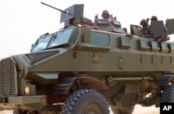 FILE - Soldiers from the Uganda People's Defense Force (UPDF) are seen driving in an armored vehicle through the streets of Bor, Jonglei State, South Sudan, Jan. 19, 2014.