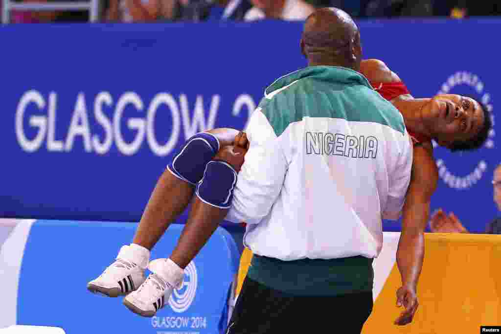 Ifeoma Nwoye of Nigeria is carried away by her coach after she lost her women&#39;s freestyle 55kg wrestling semi-final to Brittanee Laverdure of Canada at the 2014 Commonwealth Games in Glasgow, Scotland.