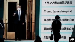 Para pejalan kaki di Tokyo, Jepang, melewati sebuah layar dengan berita Presiden Donald Trump pulang ke Gedung Putih, setelah menjalani perawatan karena terinfeksi Covid-19, 6 Oktober 2020. (Foto: AP) 
