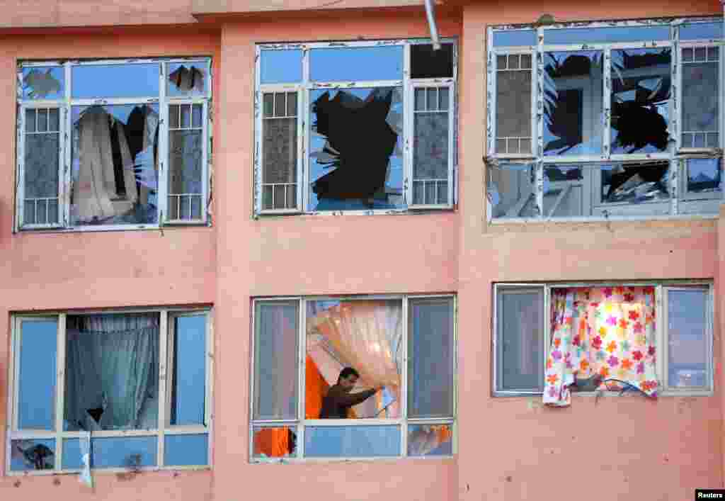 Seorang pria Afghanistan memindahkan pecahan kaca jendela dari apartemennya yang menjadi sasaran serangan bom bunuh diri di Kabul.