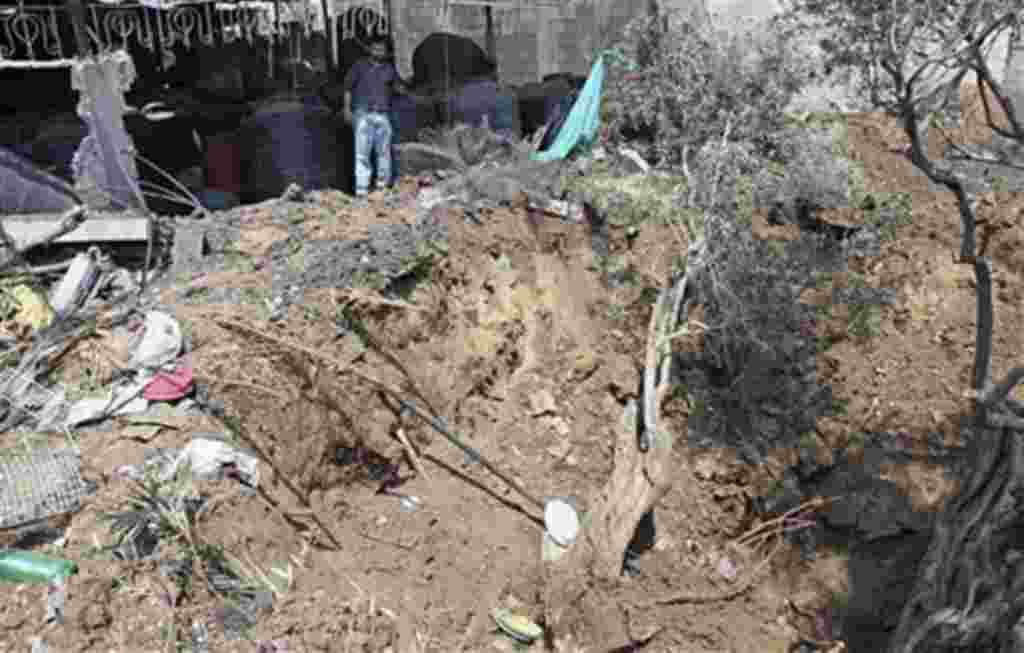 Palestinian Abdullah Fatouh inspects the damage next to his family's pickle factory after an overnight Israeli airstrike east of Gaza City, Apr 7 2011