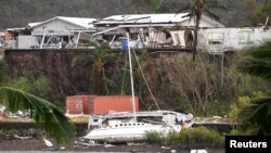A damaged building is seen behind a boat that was pushed onto a bank by Cyclone Debbie in the township of Airlie Beach, located south of the northern Australian city of Townsville, March 29, 2017.