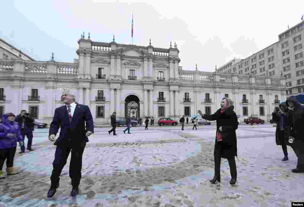Chile&#39;s President Sebastian Pinera is hit by a snowball tossed at him by his wife, first lady Cecilia Morel outside of the government palace after an unusual snowfall in Santiago, June 11, 2018.