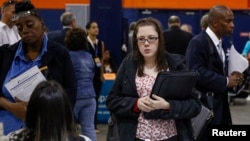 FILE - People speak with recruiters at a job fair in Uniondale, New York, Oct. 7, 2014.