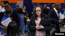 FILE - People speak with recruiters at a job fair in Uniondale, New York, Oct. 7, 2014. The U.S. economy added 267,000 jobs in January.