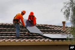 Electricians install solar panels on a roof for Arizona Public Service company in Goodyear, Arizona, June 1, 2016.