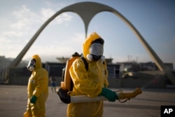 FILE - Health workers stand in the Sambadrome spraying insecticide to combat the Aedes aegypti mosquito that transmits the Zika virus in Rio de Janeiro, Brazil, Jan. 26, 2016.