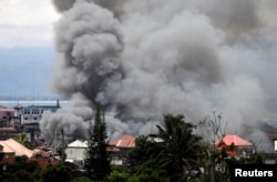 FILE - Smoke rises in the residential neighborhood of Marawi City as fighting rages between government soldiers and the Maute militant group, in southern Philippines, May 27, 2017.