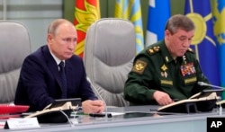 Russian President Vladimir Putin, left, and Chief of General Staff of Russia Valery Gerasimov oversee the test launch of the Avangard hypersonic glide vehicle from the Defense Ministry's control room in Moscow, Russia, Wednesday, Dec. 26, 2018