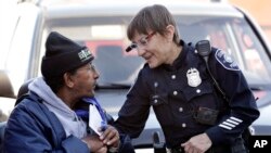 ARSIP – Petugas Kepolisian Seattle, Debra Pelich, kanan, menyematkan kamera video di kacamatanya saat ia berbincang dengan Alex Legesse sebelum pertemuan dengan masyarakat di Seattle (foto: AP Photo/Elaine Thompson, Arsip)
