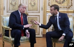 President Donald Trump and French President Emmanuel Macron gesture during their meeting inside the Elysee Palace in Paris, Nov. 10, 2018.