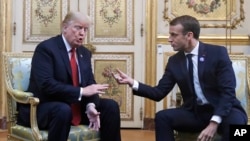 President Donald Trump and French President Emmanuel Macron gesture during their meeting inside the Elysee Palace in Paris, Nov. 10, 2018.
