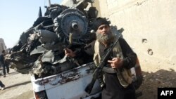 A jihadist stands next to the wreckage of a Syrian government aircraft shot down by militants of the Islamic State (IS) group over the Syrian town of Raqa on September 16, 2014. (AFP PHOTO/RMC/STR)