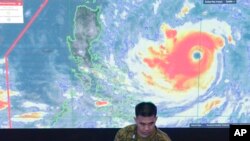 Seorang anggota Angkatan Udara Filipina berdiri di depan citra satelit Typhoon Mangkhut, yang disebut Typhoon Ompong oleh warga setempat, di pusat operasi Dewan Manajemen dan Penanggulangan di Manila, Filipina, Kamis, 13 September 2018.