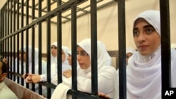 Egyptian women supporters of ousted President Mohamed Morsi stand inside the defendants' cage in a courtroom in Alexandria, Egypt, Nov. 27, 2013. 