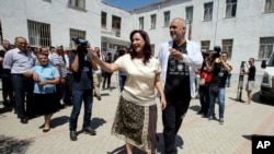 Albanian Prime Minister and leader of the Socialist party Edi Rama, right, and his wife Linda wave to supporters before casting their ballots at a polling station in Tirana outskirts, June 25, 2017.