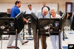 Voters cast their ballots among an array of electronic voting machines in a polling station at the Noor Islamic Cultural Center, Tuesday, Aug. 7, 2018, in Dublin, Ohio.