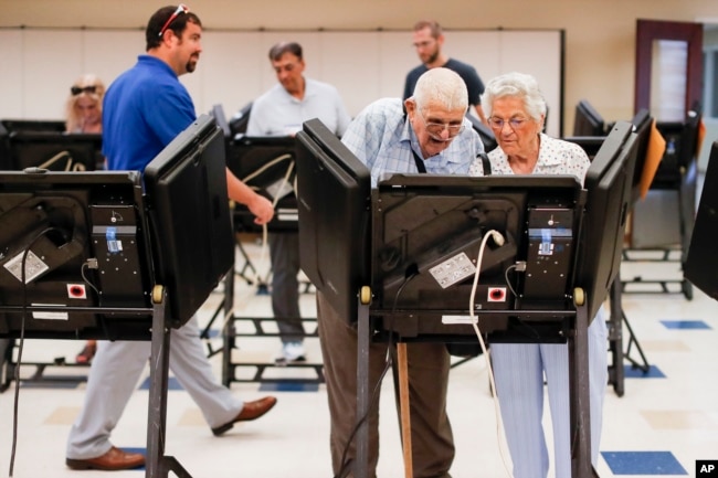 Voters cast their ballots among an array of electronic voting machines in a polling station at the Noor Islamic Cultural Center, Tuesday, Aug. 7, 2018, in Dublin, Ohio.