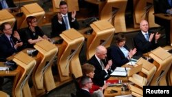 28일 영국 에딘버러 시의 스코틀랜드 의회에서 독립 추진 주민투표안이 통과된 후 의원들이 박수를 치고 있다.