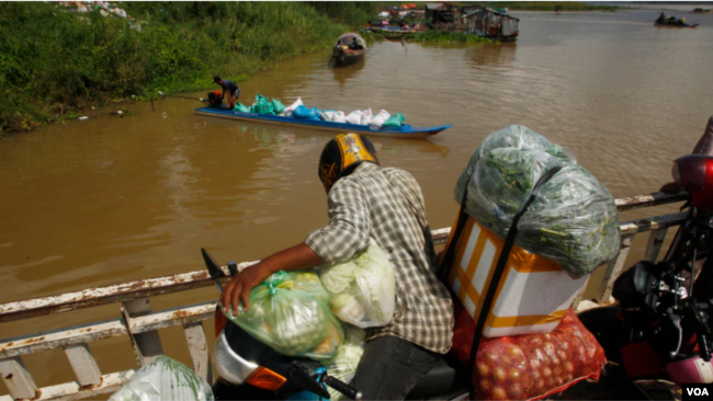 柬埔寨金边郊区的代埃特村，一名小贩和他的货物乘小船渡过湄公河。（2020年7月22日）