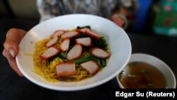 Hawker Leong Yuet Meng, 90, of Nam Seng Noodle House, sells a bowl of wonton noodle soup at her shop in Singapore. February 22, 2019. REUTERS/Edgar Su