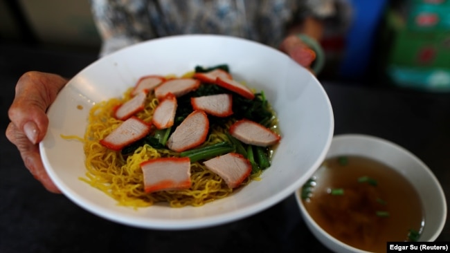 Hawker Leong Yuet Meng, 90, of Nam Seng Noodle House, sells a bowl of wonton noodle soup at her shop in Singapore. February 22, 2019. REUTERS/Edgar Su