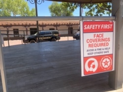 New Mexico eyaletinin Santa Fe kentinde bir mağazanın kapısında maske takmayanlara ceza uygulanacağını belirten yazı asılı