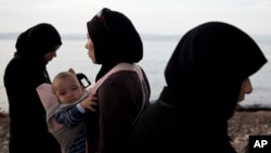 A woman refugee holds her child after arriving with others on a dinghy from Turkey at Lesbos Island, Greece, Sept. 9, 2015. 