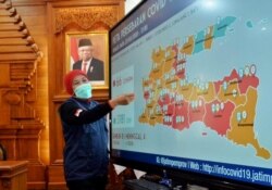 Gubernur Jawa Timur Khofifah Indar Parawansa menunjukka peta persebaran virus corona di Jawa Timur. (Foto: VOA/Petrus Riski)
