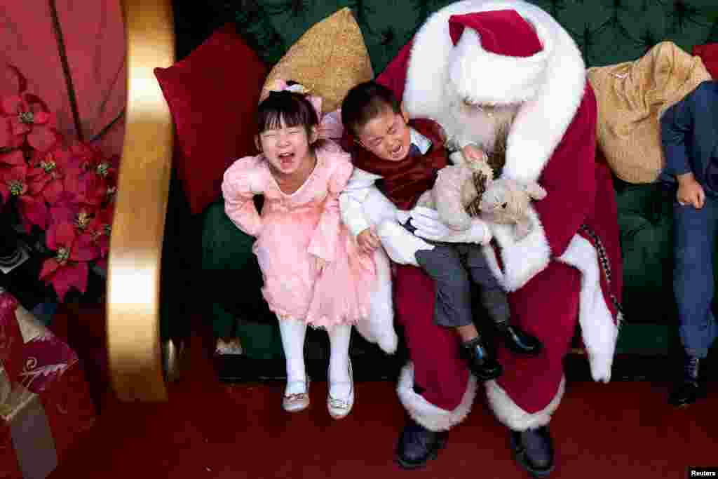 A girl laughs while her brother cries being held by Santa Claus at the King of Prussia Mall, in King of Prussia, Pennsylvania, Dec. 8, 2018.