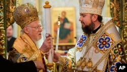 Ecumenical Patriarch Bartholomew I, left, presents the "Tomos," in a symbolic ceremony sanctifying the Ukrainian church's independence to Metropolitan Epiphanius, right, at the Patriarchal Church of St. George in Istanbul, Turkey, Jan. 6, 2019.