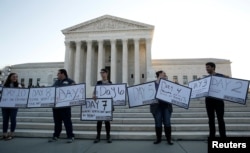 FILE - Protesters with We Need Nine, a group calling for the U.S. Senate to allow President Barack Obama to nominate a ninth Supreme Court justice, display their signs in front of the Supreme Court in Washington, D.C., Oct. 4, 2016.