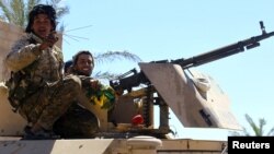 FILE - A fighter of the Syrian Democratic Forces gestures in the village of Baghuz, Deir el-Zour province, Syria, March 18, 2019.