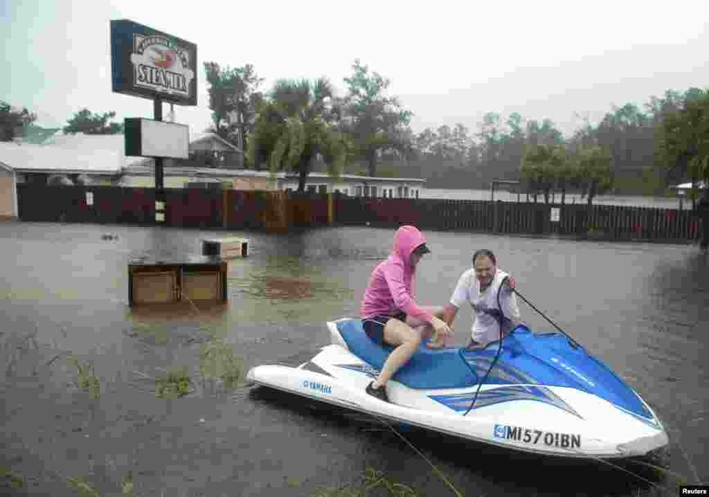 Owners Hank and Lori Plauche use a jet-ski to survey the damage to the Jourdan River Steamer, Seafood Restaurant as Hurricane Isaac passes through Kiln, Mississippi, August 29, 2012.