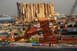 Un monument symbolisant la justice est vu en face de silos à grains gigantesques détruits lors de l'explosion massive d'août 2020 au port de Beyrouth, mercredi 4 août 2021.