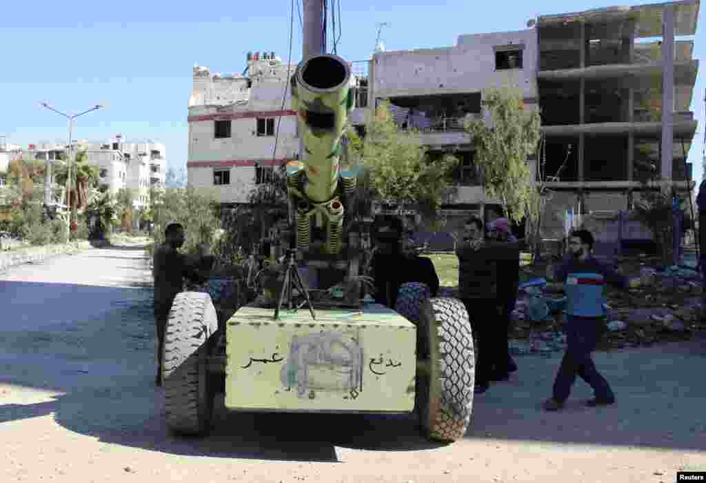 Laskar Pasukan Pembebasan Suriah bersiap untuk menembakkan meriam artileri kepada pasukan setia Presiden Suriah Bashar al-Assad di Ghouta, di timur pinggir kota Damaskus, 23 Maret 2014.
