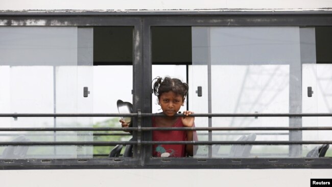 Alisha (7), melihat keluar dari jendela bus "Harapan" TejasAsia, sebuah LSM yang memanfaatkannya sebagai ruang kelas bergerak untuk anak-anak yang tinggal di daerah kumuh, di dataran banjir sungai Yamuna, New Delhi, India, 9 Agustus 2021. (REUTERS)