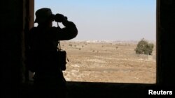 A rebel fighter looks through binoculars in Quneitra countryside, Syria, Sept. 10, 2016.