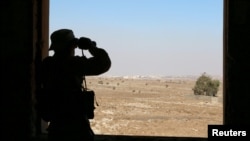 A rebel fighter looks through binoculars in Quneitra countryside, Syria, Sept. 10, 2016.