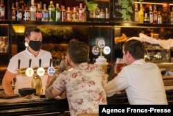 Sejumlah pelanggan menikmati minuman di bar pada hari pertama pembukaan pembatasan Covid-19 di Auckland, Selandia Baru, 3 Desember 2021. (Foto: David Rowland/AFP)