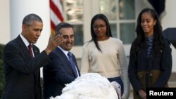 Presiden Barack Obama (kiri) memberikan pengampunan kepada kalkun bernama "Abe" dalam kegiatan tahunan ke-68 di Gedung Putih, Washington DC, untuk menyambut perayaan Thanksgiving, disaksikan kedua puterinya, Sasha dan Malia (25/11).
