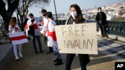 FILE - In this March 6, 2021, photo, Ksenia Ashrafullina holds a poster during a protest demanding freedom for political prisoners organized by a Belorussian cultural association, in Lisbon.